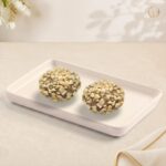 Radhe Hazelnut Almond Bomb, two hazelnut balls coated in chopped almonds on a white tray