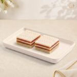 Radhe Mango Exotica, two layered squares with white chocolate top and mango jelly on a white tray